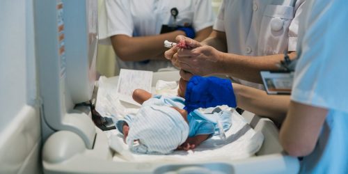 Team of professional doctors and nurses examining newborn baby at the hospital. Healthcare and medicine concept.